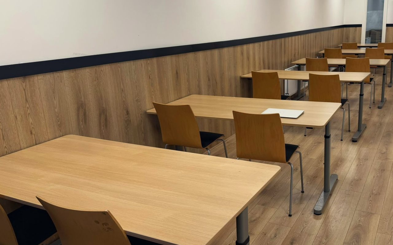 Het leslokaal van Sterren van Straks: lichte tafels en stoelen in rijen, met houten wandbekleding.